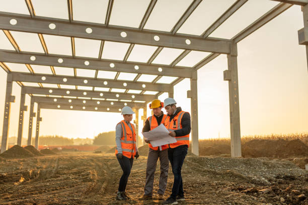 Male and female architects discussing over blueprint at construction site